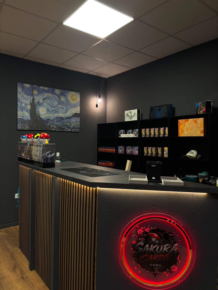 Theke mit beleuchtetem Sakura Cards Shop Logo und Regalen im Hintergrund