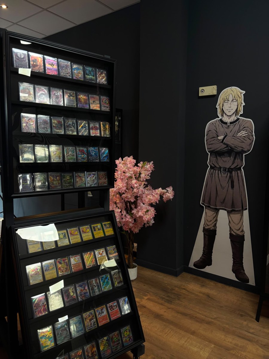 Vitrinen mit gesleevten Sammelkarten neben einem Anime-Aufsteller